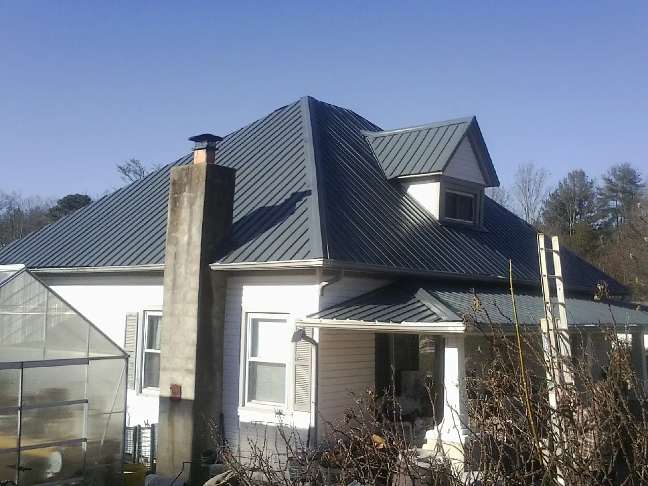 Dark blue standing seam metal roof on a white farmhouse with dormer — Slate & Tile Roof Repair by Roofing Brothers in Oriskany Falls