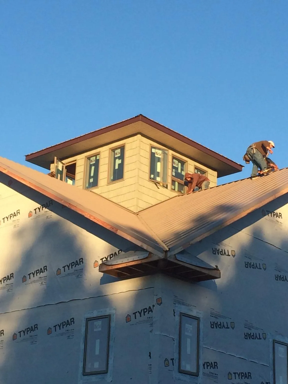 Roofers working around a rooftop cupola on a new metal roof at sunset — Roof Waterproofing in Oriskany Falls by Roofing Brothers